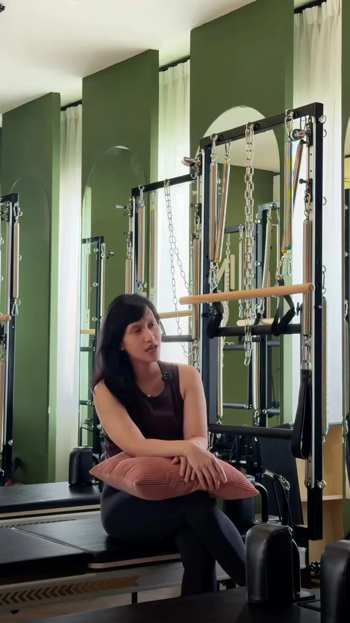 Coach Inta sitting on a reformer in front of the tower